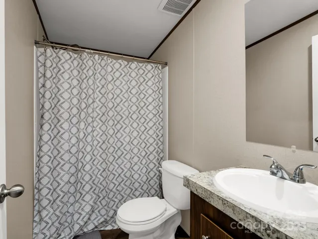 a bathroom with a granite countertop toilet and a sink