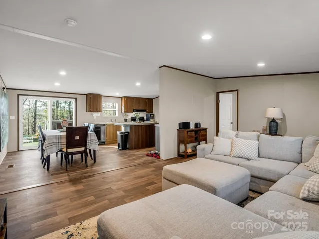 a living room with furniture kitchen view and a wooden floor