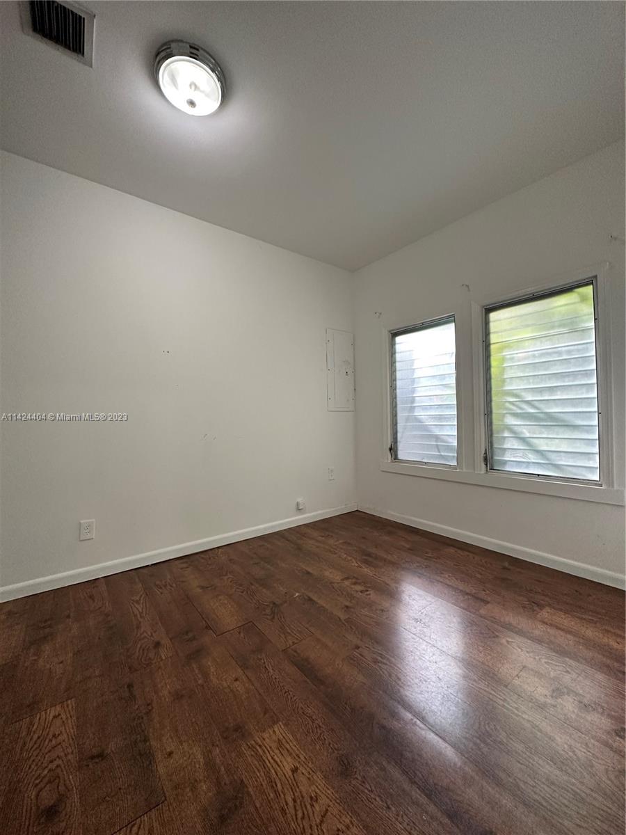 2430 Southwest 25th Terrace, Unit A Miami, FL 33133 - Photo 9 of 19 an empty room with wooden floor and windows