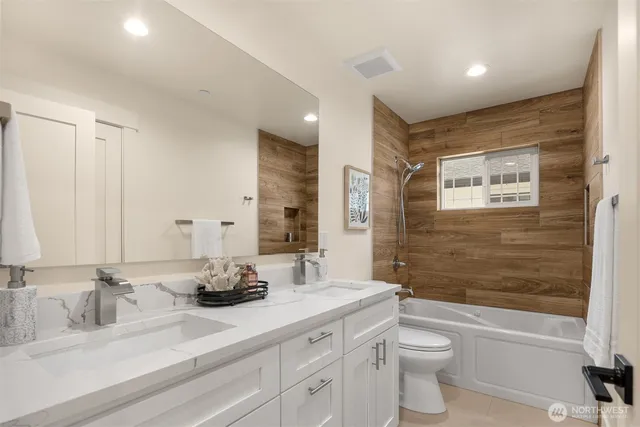 a bathroom with a double vanity sink toilet mirror and bathtub