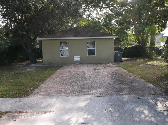 a view of a house with a yard and large tree