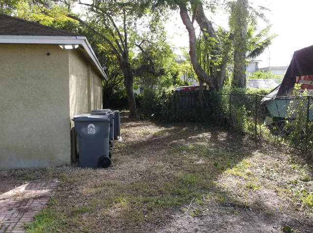 a view of a backyard with large tree and wooden fence