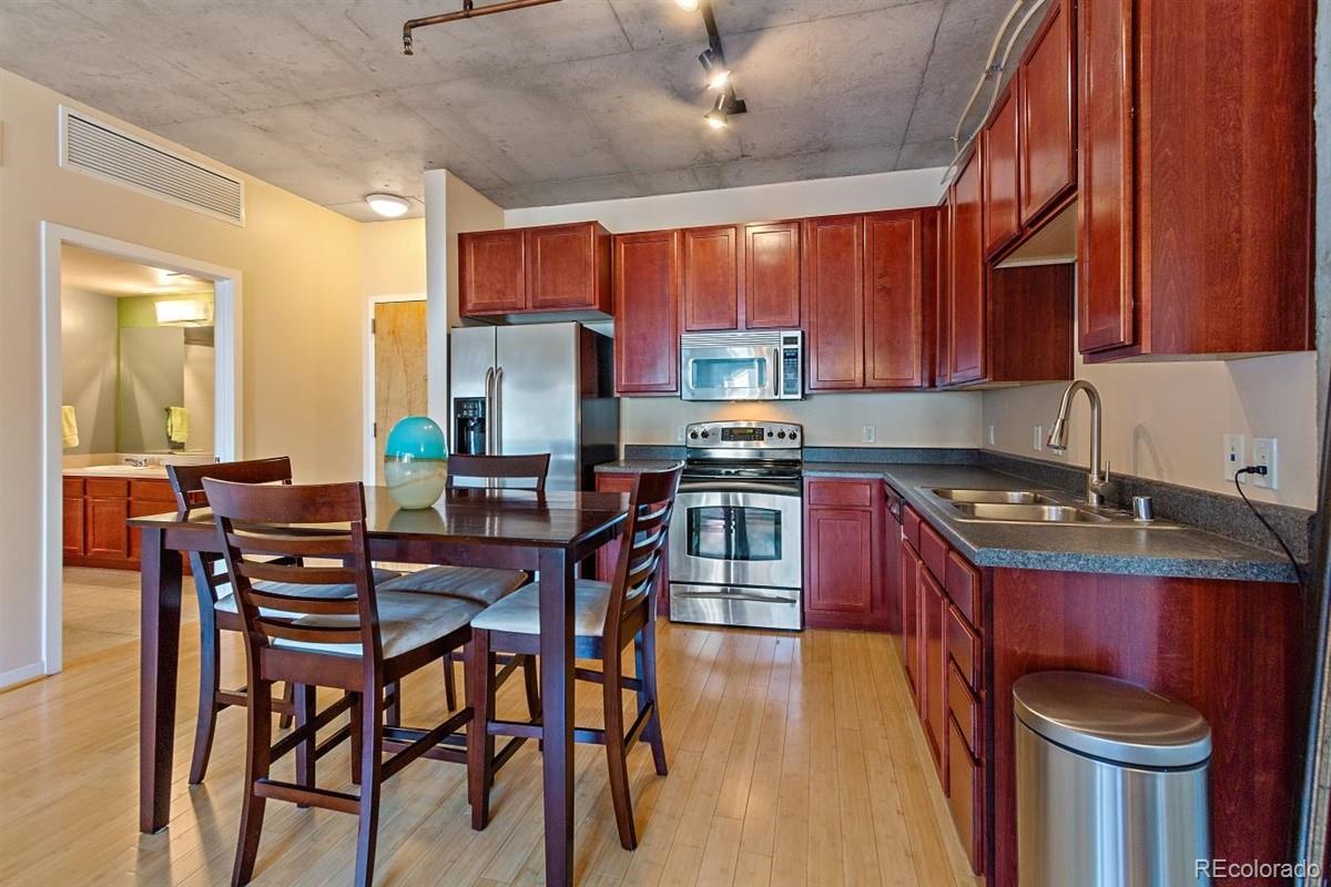 1475 Delgany Street, Unit 307 Denver, CO 80202 - Photo 5 of 18 a kitchen with stainless steel appliances a table chairs and a refrigerator