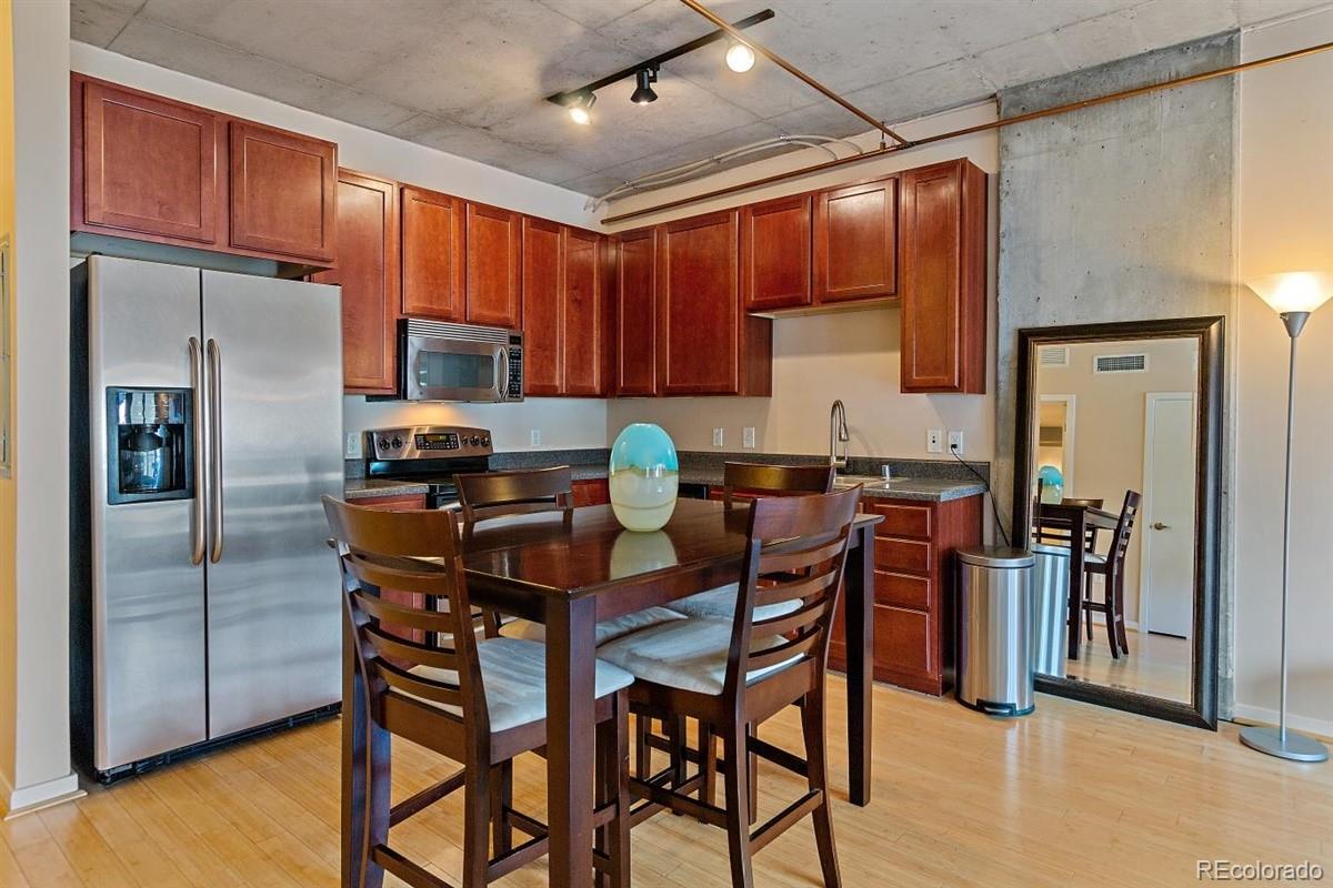 1475 Delgany Street, Unit 307 Denver, CO 80202 - Photo 6 of 18 a kitchen with stainless steel appliances granite countertop a refrigerator a sink a stove and island with wooden floor
