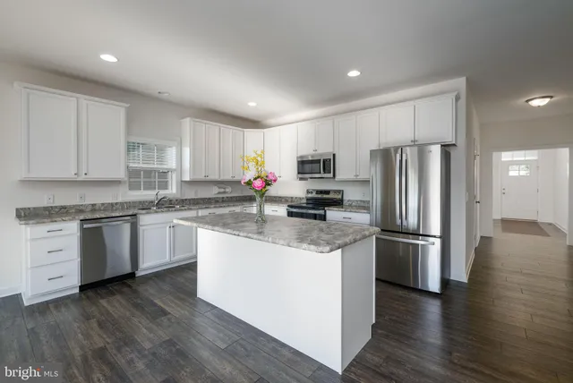 a kitchen with stainless steel appliances granite countertop a refrigerator a stove top oven a sink and cabinets