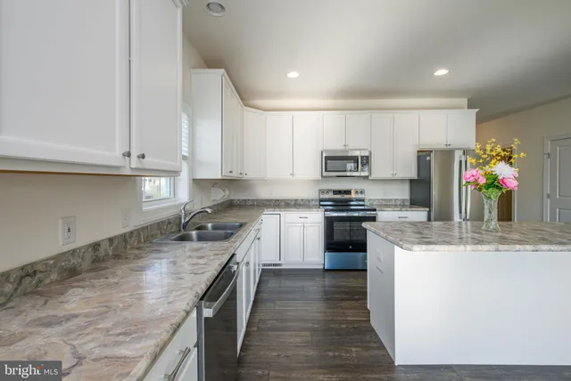 a kitchen with stainless steel appliances granite countertop a stove a sink and a refrigerator
