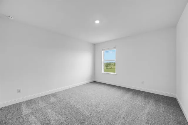 a view of an empty room and chandelier fan