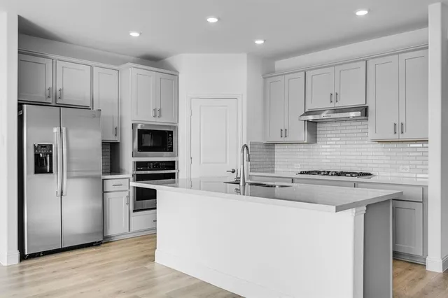 a kitchen with kitchen island a sink stainless steel appliances and cabinets