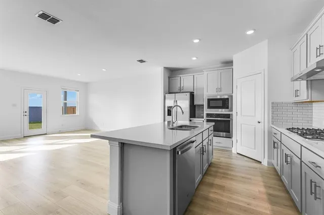 a kitchen with stainless steel appliances granite countertop a sink stove and refrigerator