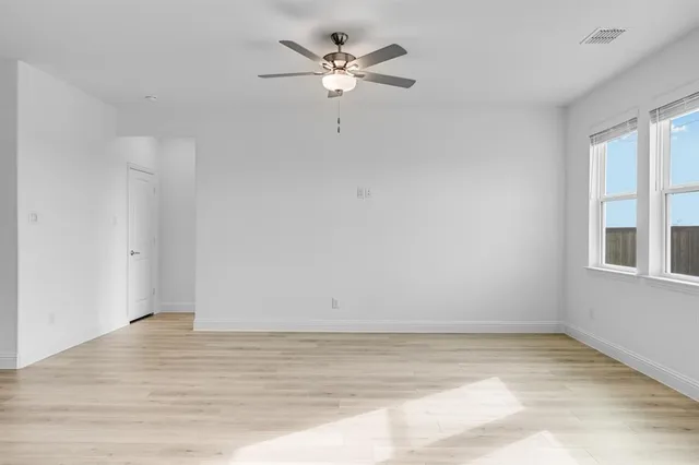 a view of an empty room with a window and wooden floor