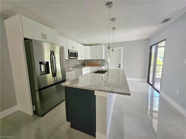 a kitchen with stainless steel appliances granite countertop a refrigerator a sink a stove and a refrigerator