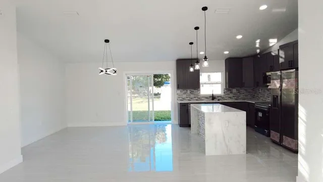 a large kitchen with granite countertop a large kitchen island white cabinetry and refrigerator