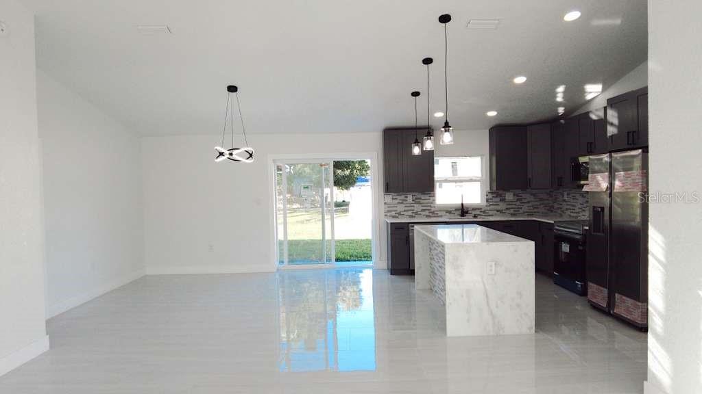 4115 El Rado Avenue Sebring, FL 33872 - Photo 3 of 31 a large kitchen with granite countertop a large kitchen island white cabinetry and refrigerator