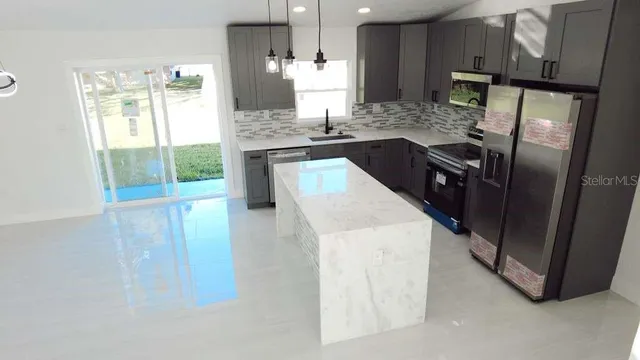 a kitchen with stainless steel appliances granite countertop a refrigerator a stove and a sink