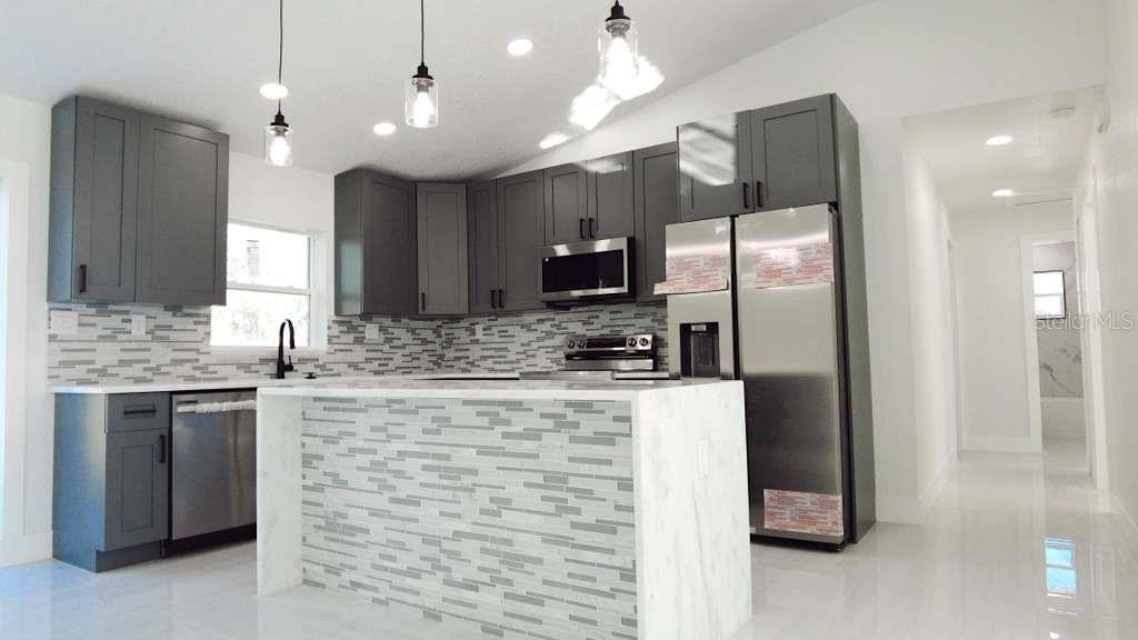 4115 El Rado Avenue Sebring, FL 33872 - Photo 10 of 31 a large kitchen with stainless steel appliances kitchen island granite countertop a refrigerator and a sink