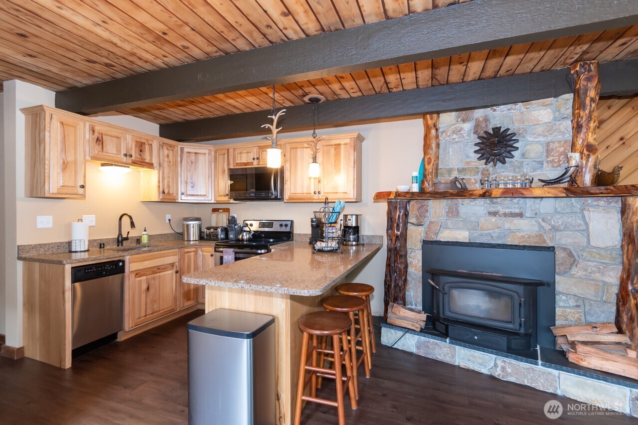 90-92 Mallard Cove Road Port Angeles, WA 98363 - Photo 29 of 40 a kitchen with stainless steel appliances granite countertop a stove top oven a sink dishwasher and a fireplace with wooden floor
