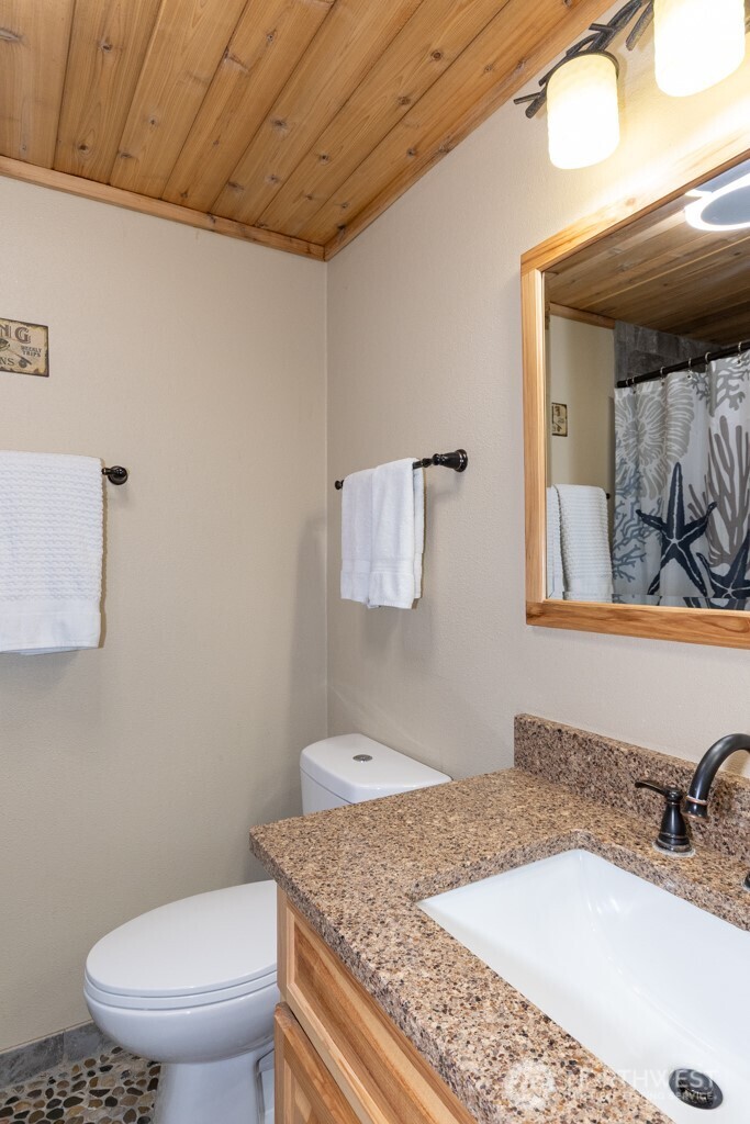 90-92 Mallard Cove Road Port Angeles, WA 98363 - Photo 35 of 40 a bathroom with a granite countertop sink a mirror and a toilet