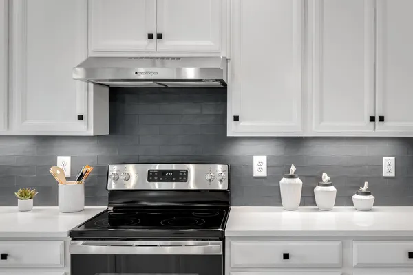 a kitchen with stainless steel appliances kitchen island granite countertop a refrigerator a stove and white cabinets with wooden floors