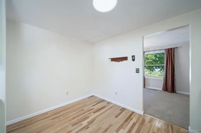 a view of a room that has wooden floor and a window