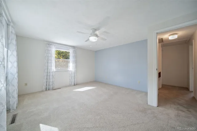 an empty room with windows and fan