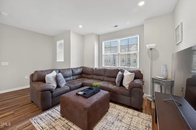 a living room with furniture a flat screen tv and a window