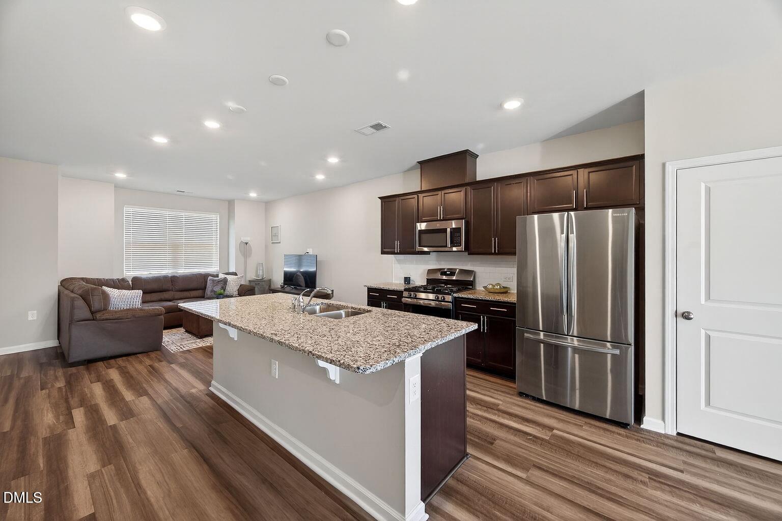 1063 Shoreside Drive Durham, NC 27713 - Photo 11 of 35 a large kitchen with stainless steel appliances kitchen island a stove a refrigerator a couch and a view of living room