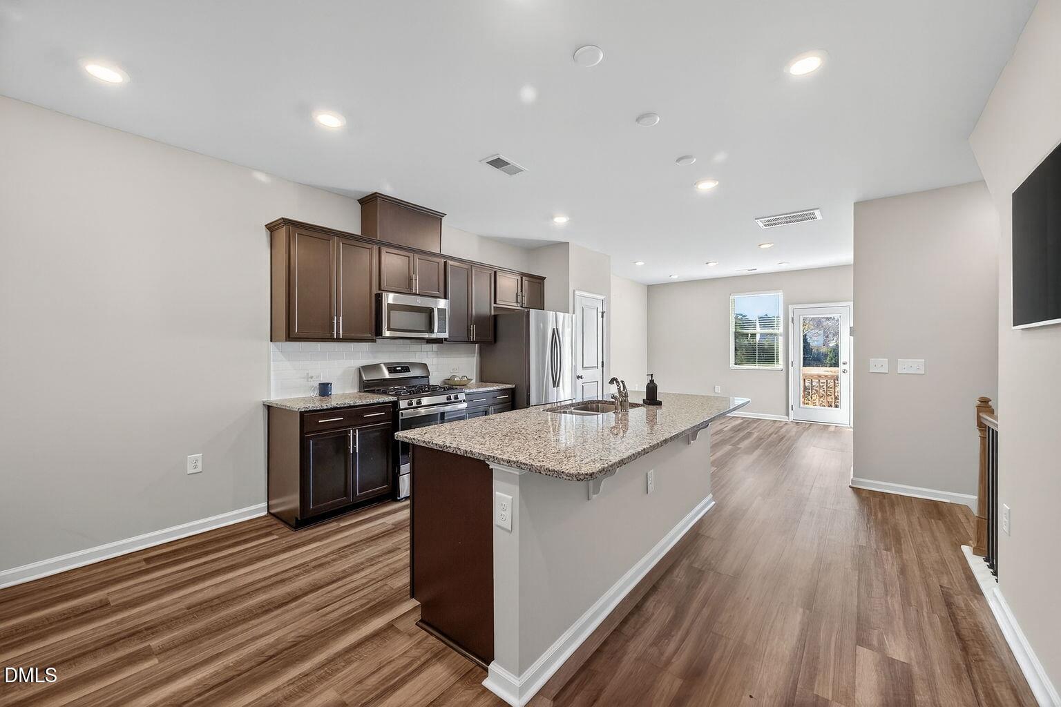 1063 Shoreside Drive Durham, NC 27713 - Photo 12 of 35 a kitchen with stainless steel appliances granite countertop a sink stove and refrigerator