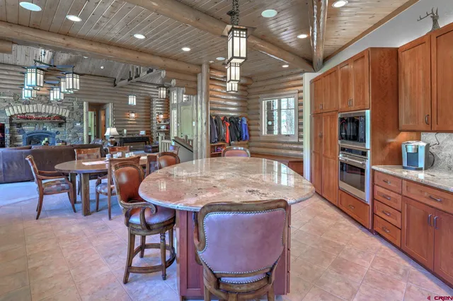 a kitchen with stainless steel appliances granite countertop a stove a refrigerator a oven a sink with a dining table and chairs