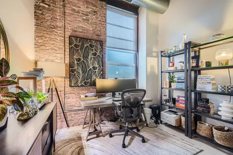 a view of a workspace with furniture and a window