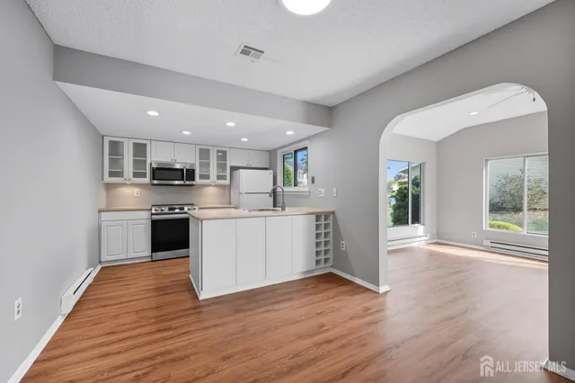 a kitchen with stainless steel appliances granite countertop a stove a sink dishwasher and a refrigerator with wooden floor