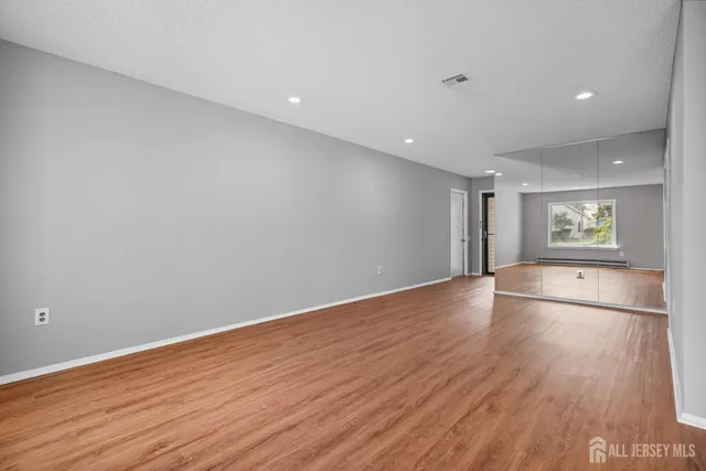a view of empty room with wooden floor and fan