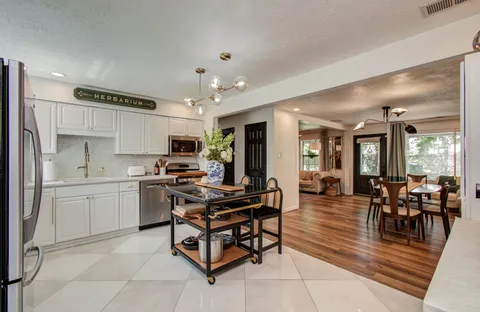 a kitchen with stainless steel appliances kitchen island granite countertop a table chairs sink and cabinets