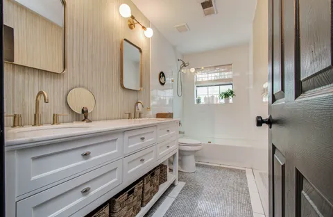 a bathroom with a double vanity sink toilet mirror and window