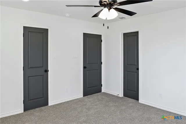 an empty room with closet and a chandelier fan