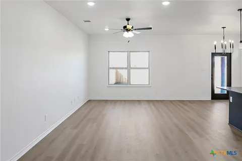 an empty room with windows and chandelier fan