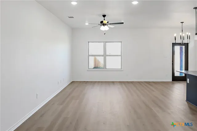 an empty room with windows and chandelier fan