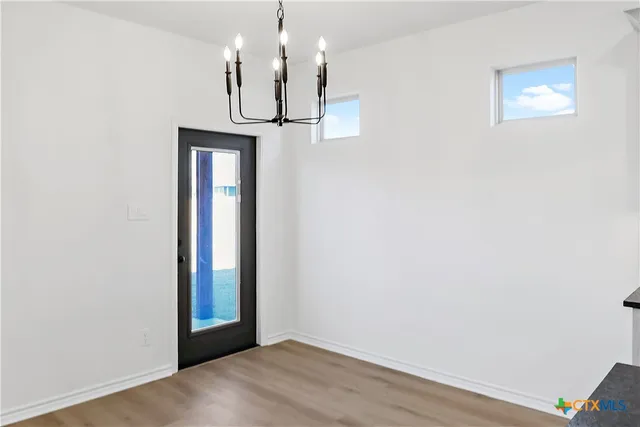 a view of a hallway with wooden floor and chandelier