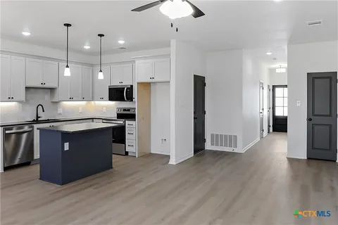 a kitchen with stainless steel appliances granite countertop a refrigerator a sink a stove a microwave and wooden floor