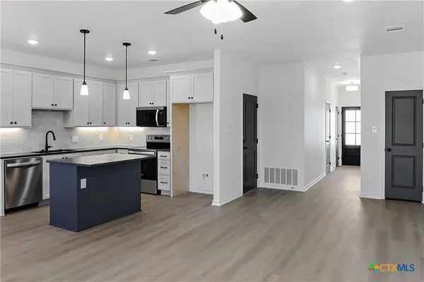 a kitchen with stainless steel appliances granite countertop a refrigerator a sink a stove a microwave and wooden floor