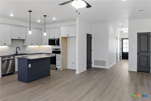 a kitchen with stainless steel appliances granite countertop a refrigerator a sink a stove a microwave and wooden floor