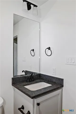 a bathroom with a granite countertop sink and a mirror
