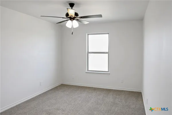 an empty room with a window and a fan