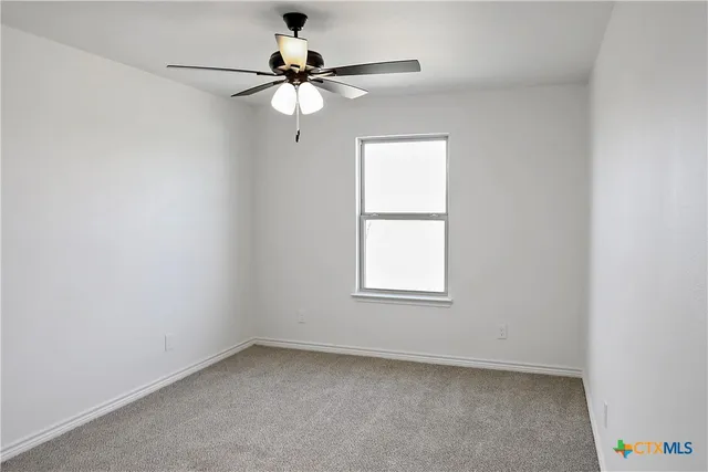 an empty room with a window and a fan