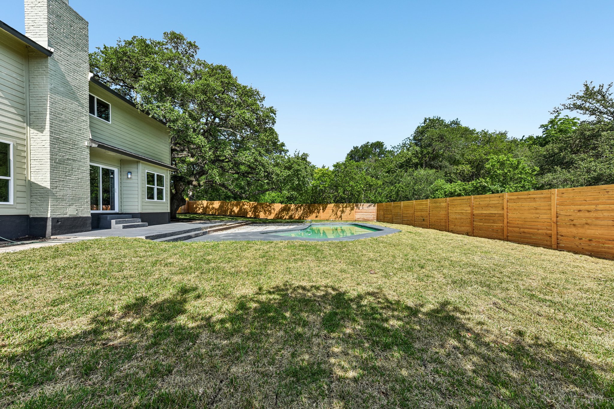 7523 Glenhill Road Austin, TX 78752 - Photo 33 of 38 A private yard with a refreshing pool, ample green space, and a wooden privacy fence.