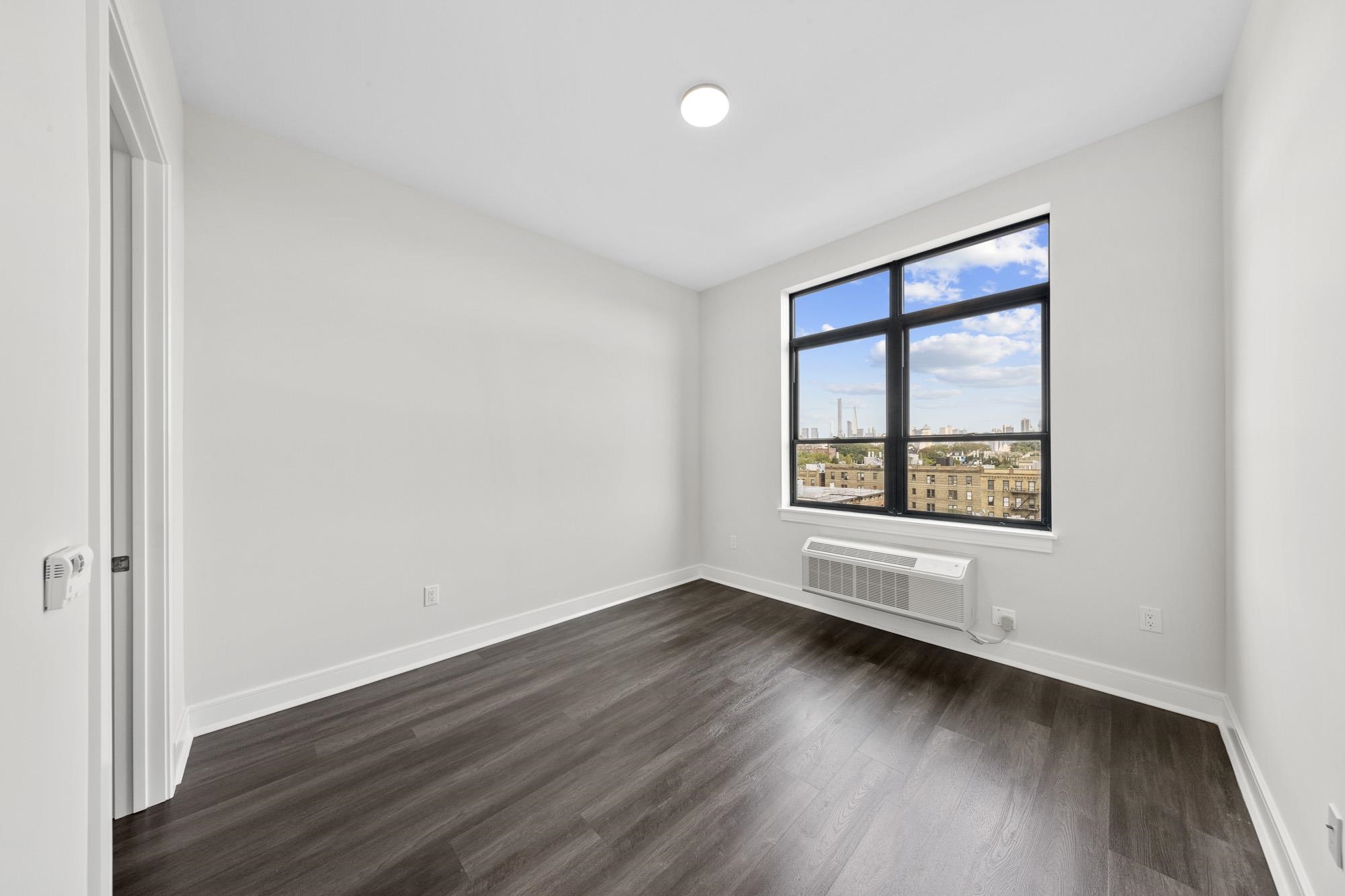 121 34th Street, Unit 604 Union City, NJ 07087 - Photo 8 of 44 an empty room with wooden floor and windows