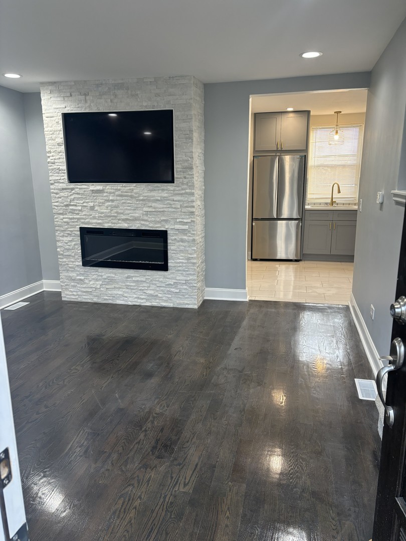 2049 East 93rd Street Chicago, IL 60617 - Photo 2 of 19 a living room with a fireplace a flat screen tv and a fireplace
