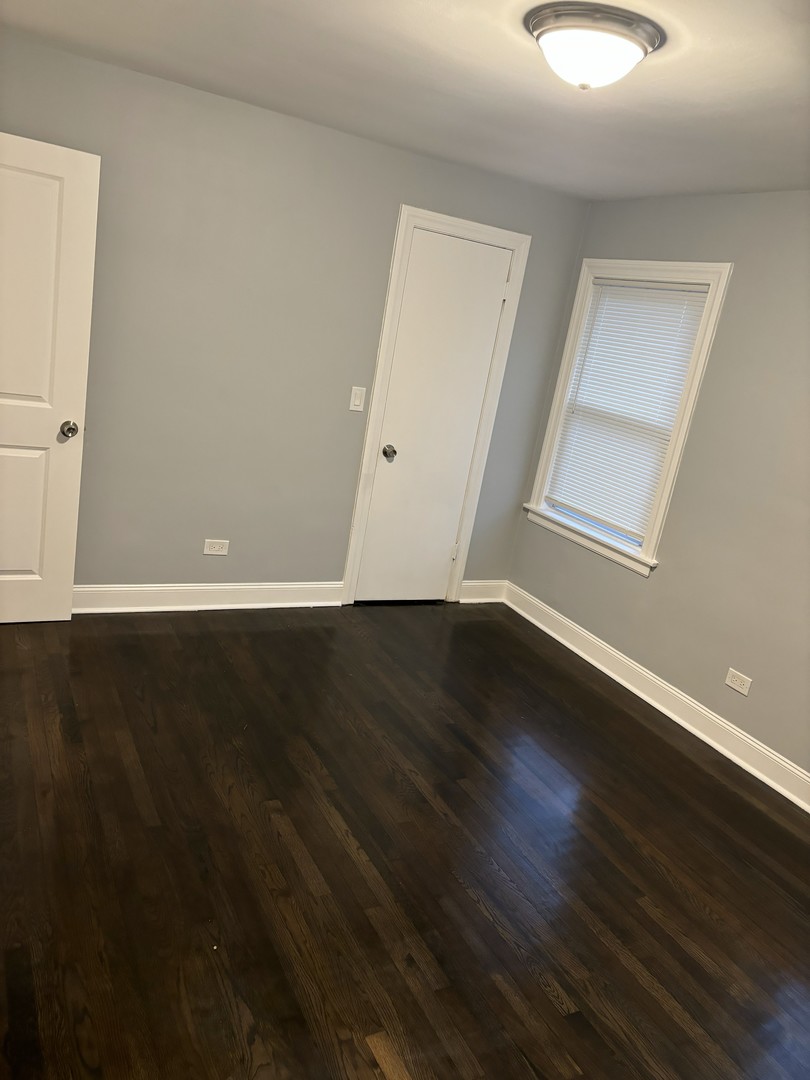 2049 East 93rd Street Chicago, IL 60617 - Photo 8 of 19 a view of an empty room with wooden floor and a window