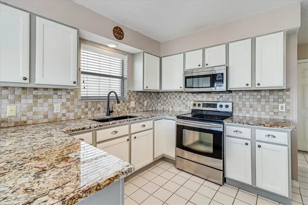 a kitchen with granite countertop a sink stove and refrigerator