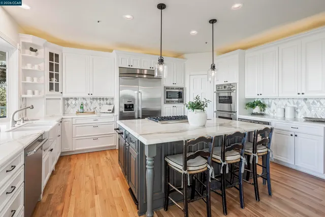 a kitchen with stainless steel appliances kitchen island granite countertop a table chairs sink and cabinets