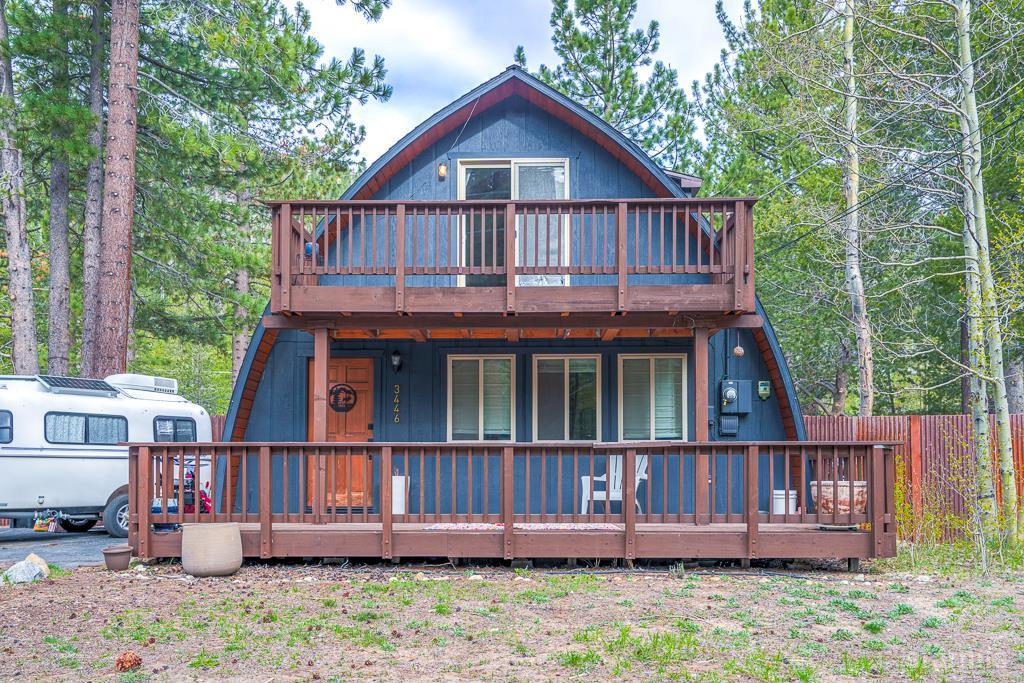 a view of wooden house with a yard and deck